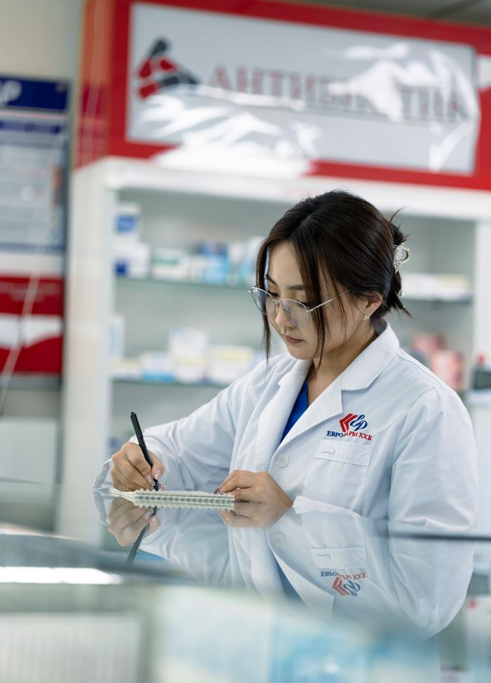 heros-img Female pharmacist taking notes in a pharmacy environment.