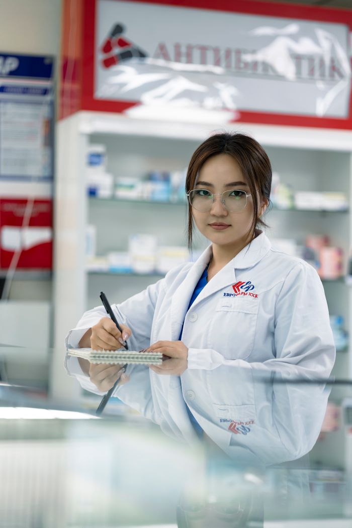 about-us-01 Female pharmacist writing in notepad inside a pharmacy.